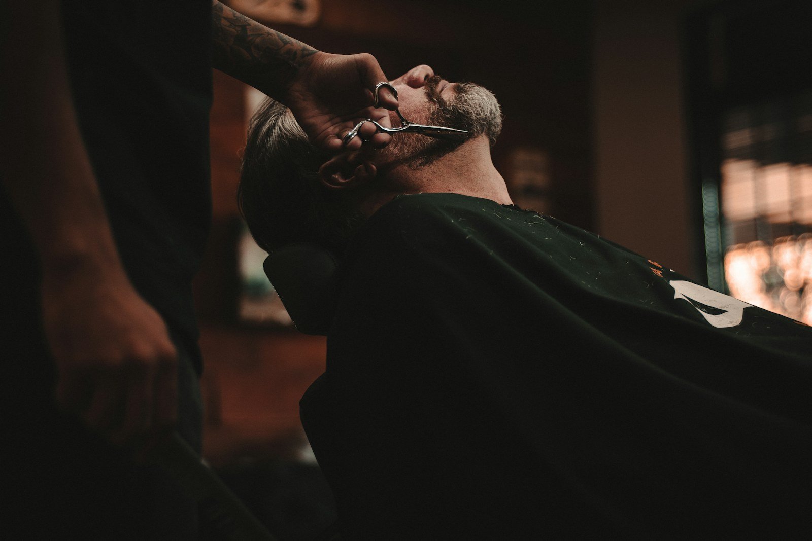 Barber carefully trimming a client's beard